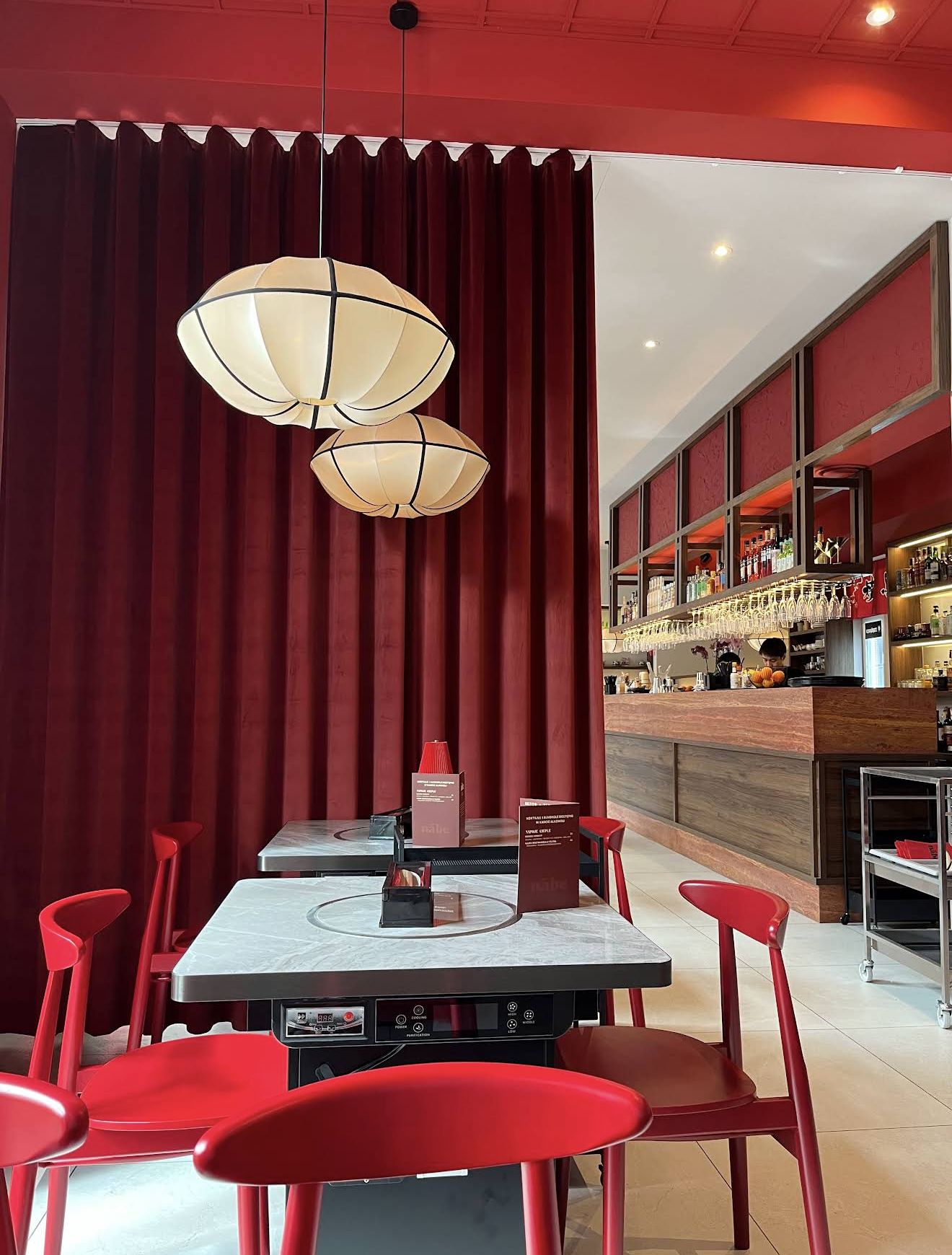 Dining room with red velvet curtains, paper lanterns and red chairs